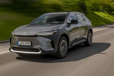 Grå Toyota bZ4X kör på en väg, med grönskande natur i bakgrunden. Ett potentiellt toyota bz4x problem kan vara dess räckvidd.
