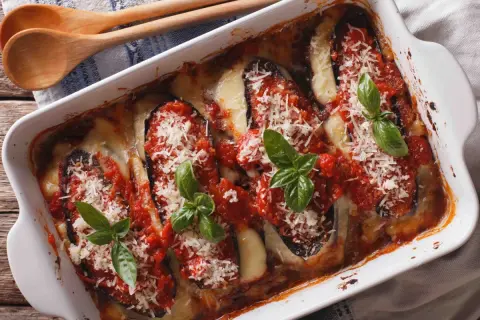 Un plat de parmigiana sicilienne tout juste sorti du four, avec des aubergines, de la sauce tomate, du fromage fondant et du basilic frais.