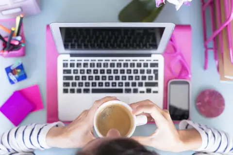 Kawa i laptop na biurku, inspiracja do tego, jaką firmę założyć.