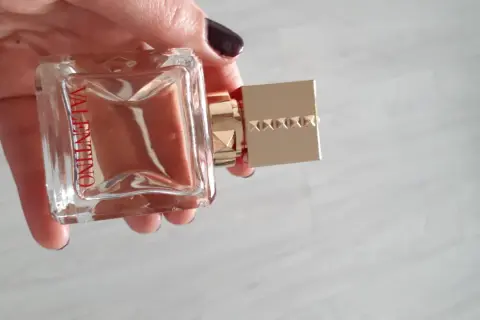 Elegancki flakon Valentino Voce Viva 100ml w dłoni, z charakterystycznym złotym korkiem ozdobionym ćwiekami.