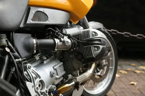 Zbliżenie na silnik motocykla z żółtym bakiem i elementami układu paliwowego.