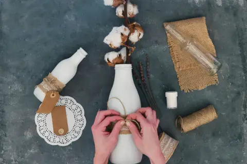 Ręce wiążą sznurkiem butelkę, tworząc ozdobę. Idealne pomysły, co można zrobić na Dzień Chłopaka DIY.