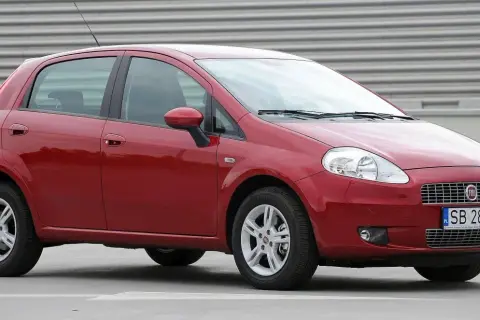 Czerwony Fiat Grande Punto, przód. Wymiana żarówki w reflektorze przednim jest prosta.