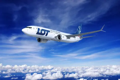 Samolot LOT Polish Airlines leci na tle błękitnego nieba z chmurami.