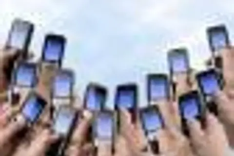 Ręce trzymają telefony komórkowe, gotowe do wysłania pustego SMS-a na loterię.