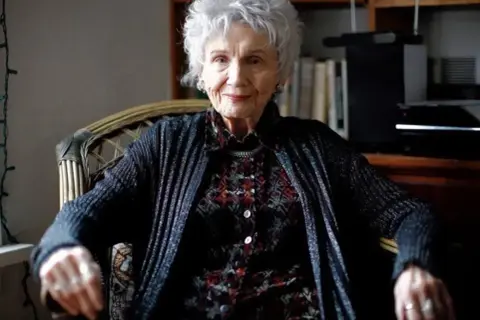 Portret starszej kobiety, kanadyjskiej pisarki noblistki Alice Munro, siedzącej w fotelu.