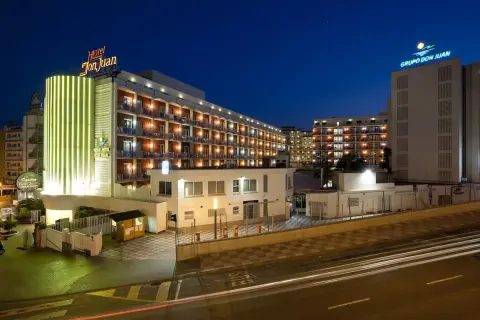 Gran Hotel Don Juan Resort nocą, z podświetloną fasadą i oknami.
