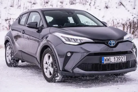 Szary Toyota C-HR Hybrid na śniegu, gotowy na zimowe wyzwania.