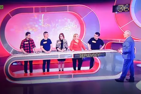 Uczestnicy teleturnieju, w tym rodzina pracowników TVP, czekają na rozpoczęcie gry.