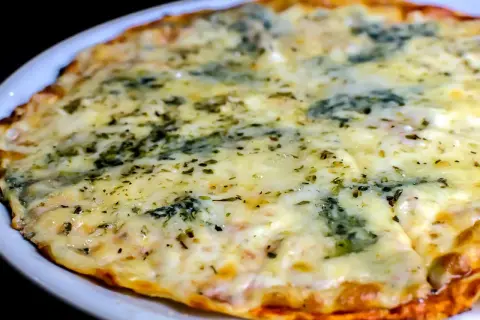 Eine köstliche quattro formaggi pizza mit geschmolzenem Käse und Kräutern, serviert auf einem weißen Teller.