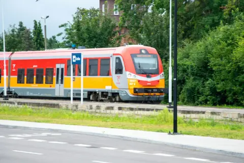 Czerwono-żółty pociąg Polregio na tle zieleni. Czy w Polregio jest rezerwacja miejsc?