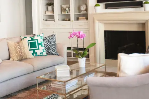 A sofa with pillows showcasing mixing patterns: a fawn print, a bold green geometric, and a black and white ikat.