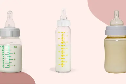 Two glass baby bottles filled with milk sit beside a plastic one, showcasing the difference between glass baby bottles vs plastic.