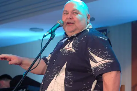 Mężczyzna w koszuli z żaglówkami śpiewa przy mikrofonie. Może to opowieść o córce rybaka i wałach jagiellońskich?