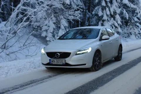 Białe Volvo V40 D3 pokonuje ośnieżoną drogę w lesie.