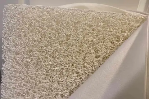 Close-up of a white, airy, woven material, revealing what the Newton mattress is made of: a breathable, open-cell core.