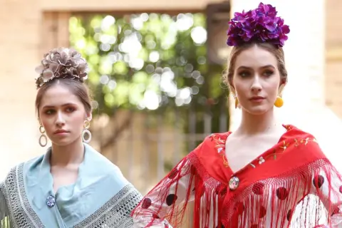 Dos jóvenes con maquillaje flamenca, flores en el pelo y mantones de seda.