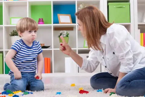 Mamma che si arrabbia con i figli piccoli, puntando il dito contro il bambino che fa il broncio.