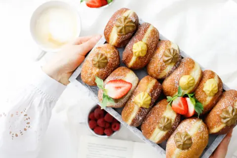 Frisch gebackene Faschingskrapfen mit Puderzucker, Erdbeeren und einer Tasse Kaffee. Ein Genuss zum Fasching!