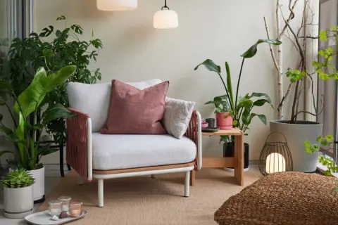 Gemütliche loggia balkon mit Sessel, Kissen, Pflanzen und Laterne.