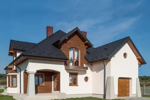 Nowoczesny dom z drewnianymi elementami i białym tynkiem. Solidny cokół na elewacji chroni budynek.