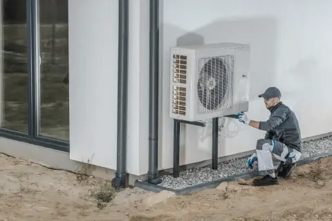Tecnico che installa una pompa di calore esterna, un sistema efficiente per riscaldare e raffreddare la casa.