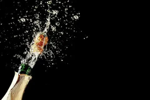 Champagnerkorken spritzt mit Flüssigkeit aus einer Flasche. Perfekt für den Moment, wenn man Champagner lagern und dann genießen möchte.