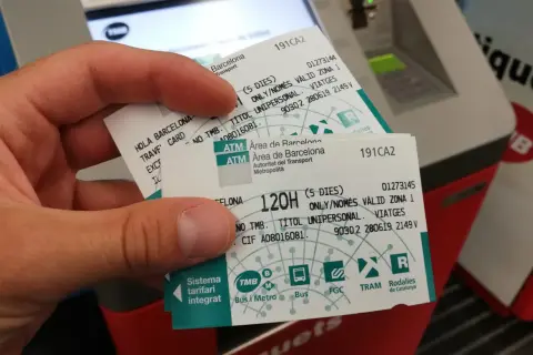Dłoń trzyma bilety na Barcelona komunikacja miejska. Widać logo TMB i nazwy środków transportu.