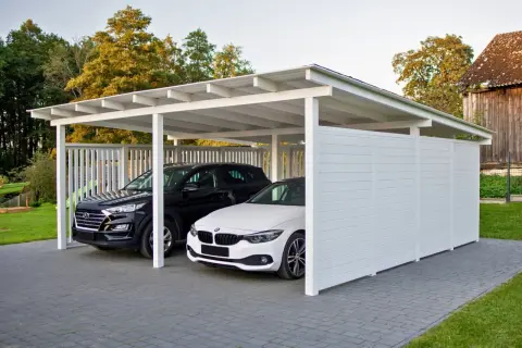 Nowoczesna wiata przy domu chroni dwa samochody: czarnego SUV-a i białe BMW.