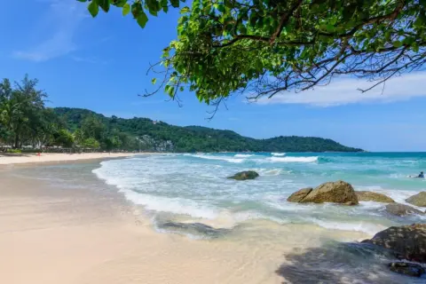 Piękna plaża Kata Beach z turkusową wodą, falami i palmami. Idealne miejsce na relaks.