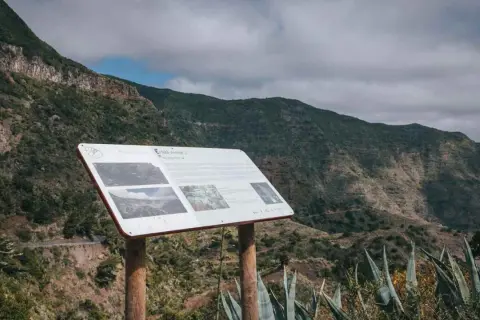 Panel informativo en el mirador de Carboneras, con vistas a un valle montañoso cubierto de vegetación.