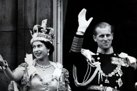 La reina Isabel II, con su corona, y el príncipe Felipe saludan tras su coronación.