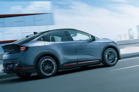 En blå Nissan Leaf 2026 glider fram på en motorväg med en stadssilhuett i bakgrunden.