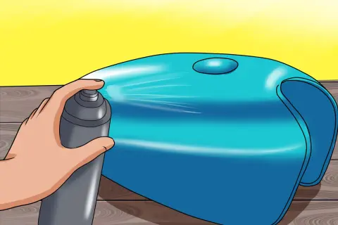Mano che spruzza vernice su un serbatoio di moto blu, per verniciare serbatoio moto e dargli un nuovo look.