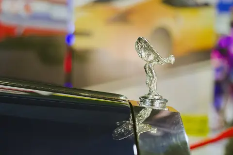 Den ikoniska Rolls-Royce kylarprydnad, "Spirit of Ecstasy", glänser på en mörk bil.