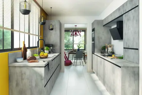 Cuisine moderne avec des meubles gris béton, une cuisine en parallèle fonctionnelle et un espace repas lumineux visible à travers une arche.