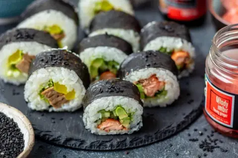 Pyszne domowe sushi z łososiem i awokado, gotowe do podania z imbirem i sezamem.
