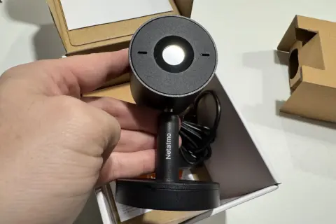 Main tenant de la nouvelle installation camera Netatmo. Le produit est dans sa boîte, prêt à être mis en place.
