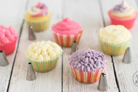 Bunte Cupcakes mit verschiedenen **cupcake topping** Mustern, umgeben von Spritztüllen.