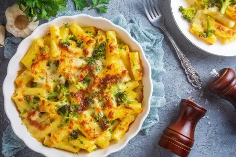Zapiekanka makaronowa z brokułami i serem, posypana natką pietruszki.