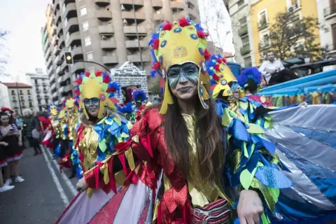 Gente disfrazada con trajes coloridos y elaborados desfila en los carnavales de Zaragoza, celebrando con alegría y arte.