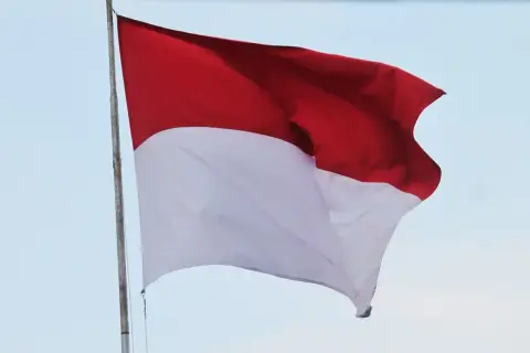 Flaga Indonezji powiewa na wietrze, ukazując swoje dumne czerwono-białe barwy na tle błękitnego nieba.