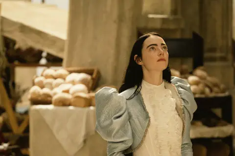 Bella Baxter blickt hoffnungsvoll gen Himmel, während sie auf dem Markt steht. Ein Bild, das Lust macht, "Poor Things" zu streamen.