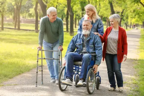 Uśmiechnięci seniorzy spacerują po parku. Warto zabrać do sanatorium w Ustroniu wygodne ubrania i dobry humor.