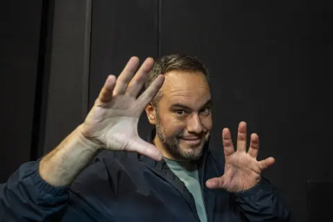 Jorge Blass Zaragoza, ilusionista, sonríe con las manos extendidas, listo para un truco.