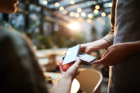 Klient płaci kartą z telefonu zbliżeniowo przy terminalu. Szybko i wygodnie.