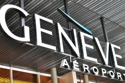 Napis "GENEVE AEROPORT" na tle nowoczesnej architektury, symbolizujący jedne z wielu lotnisk w Szwajcarii.