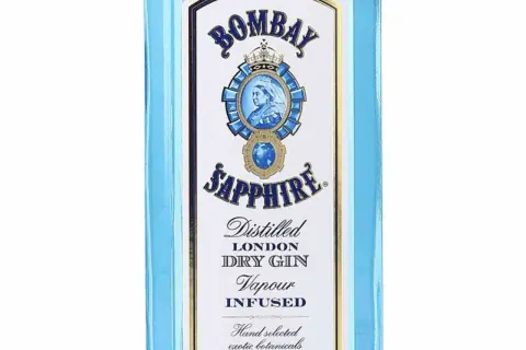 Niebieska butelka z etykietą Bombay Sapphire, na której widnieje portret królowej i napis "Distilled London Dry Gin".