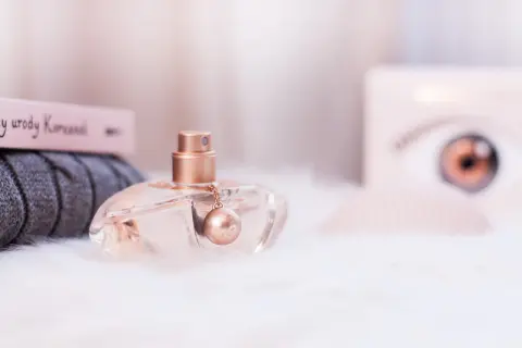 Eleganckie perfumy Kenzo World w szklanym flakonie z złotym detalem, otoczone miękkim futerkiem i książką o urodzie.