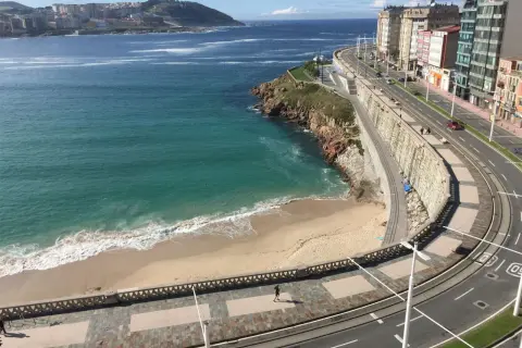 Una de las 10 mejores playas de A Coruña, con arena dorada, mar turquesa y un paseo marítimo con edificios modernos.